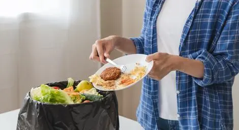 Person scraping food into a bin. 