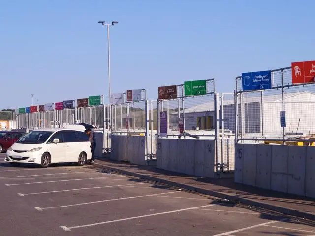 White car parked in front of a recycling centre