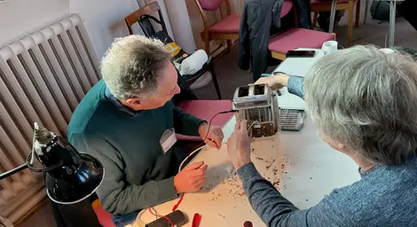 Two people rebuilding a metal toaster