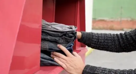 Hands pushing a bundle of clothes into a clothes bank